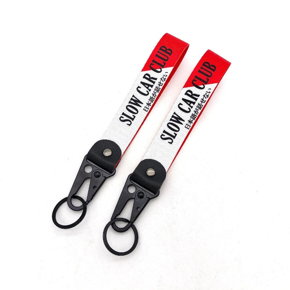 Red and white striped nylon keychain with a steel clip featuring the text SLOW CAR CLUB