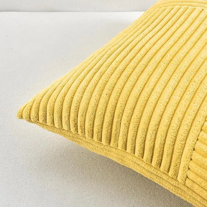 A close-up view of a yellow corduroy patchwork throw pillow cover with vertical ribbing.