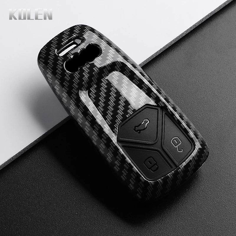 A black carbon fiber style key fob cover for an Audi, shown in a close-up view.