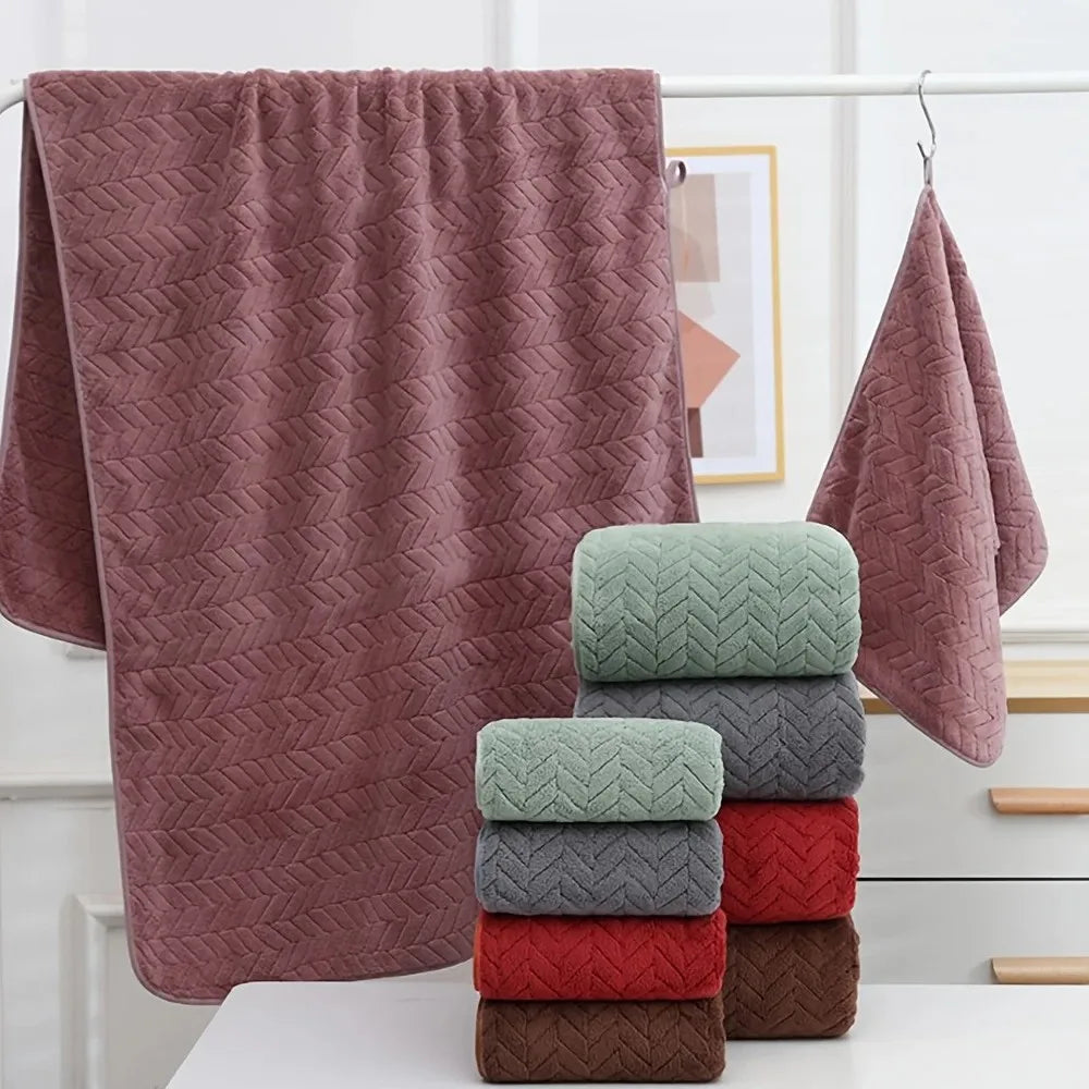 A stack of soft, coral velvet bath towels in various shades of pink and gray are displayed on a white shelf.