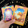 A hand holds a yellow tarot oracle deck featuring an illustration of a bright, glowing sun and landscape.