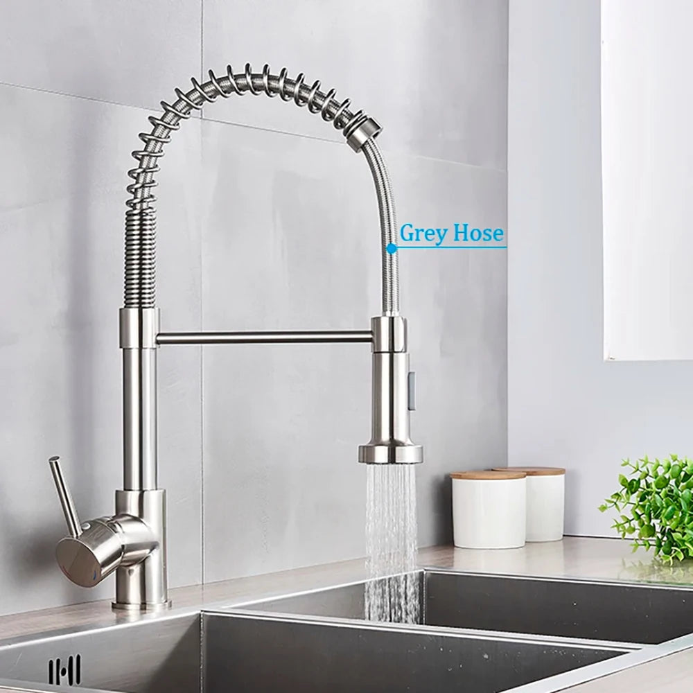 A matte black pull-down kitchen faucet with a flexible spray head is installed above a stainless steel sink.
