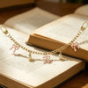 Gold alloy chain with pink bow decorations resting on an open book.