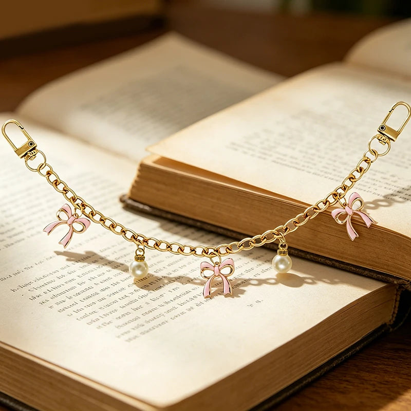 Gold alloy chain with pink bow decorations resting on an open book.