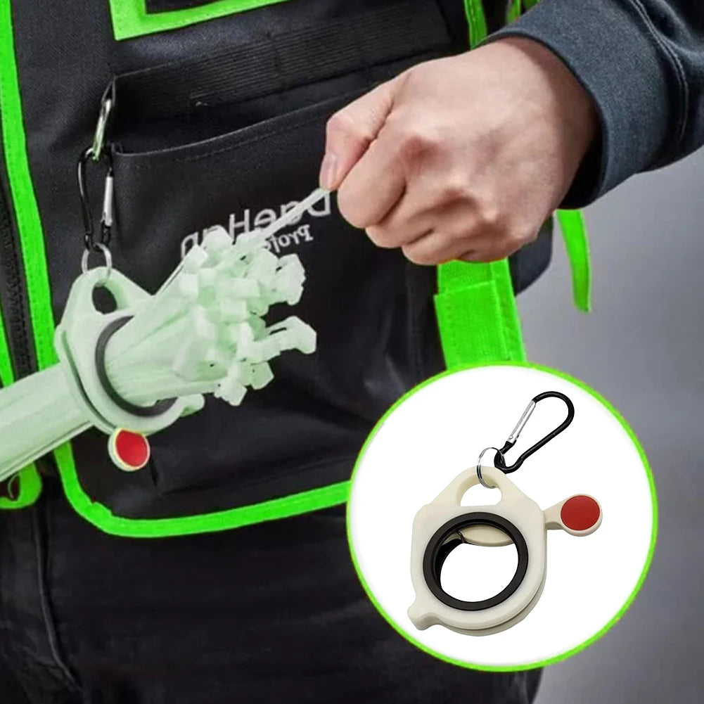 A hand is clipping a glow-in-the-dark cable tie organizer with a carabiner onto a black tactical vest.