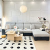 A modern light gray sofa with a dark accent, featuring a white and black patterned rug in a bright living room.