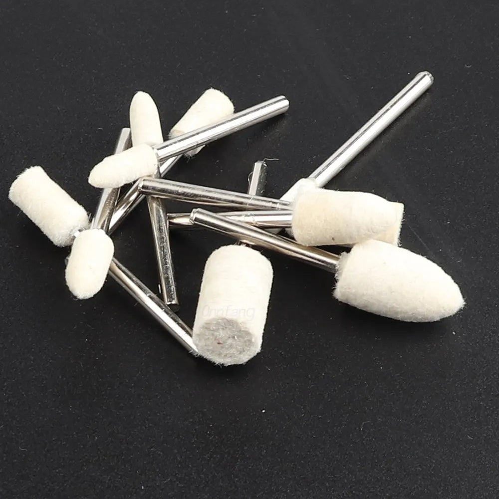 A collection of white wool felt polishing wheels with metal shafts arranged on a dark surface.