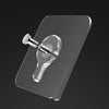A transparent self-adhesive hook is shown mounted on a dark surface.