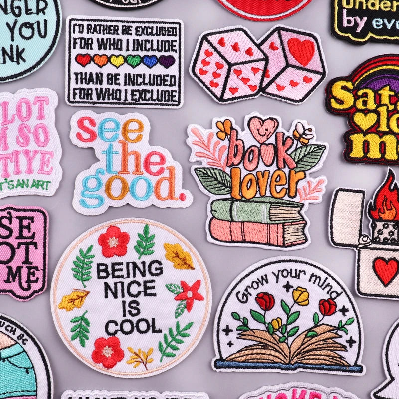 A collection of embroidered iron-on patches featuring various phrases and designs on a light gray background.