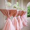 Pink satin tablecloths draped in elegant folds with white floral arrangements in a bright indoor setting.