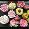 A collection of pink and yellow 3D rose peony silicone molds for crafting candles, soap, and baking.