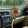 A gold-tone Islamic calligraphy pendant hangs from a chain, displayed inside a car interior.