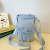 Light blue bow-decorated casual crossbody bag with adjustable strap resting on a light surface.
