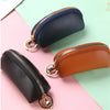 A set of three PU leather key organizer wallets in black, navy blue, and brown leather with gold-toned zippers