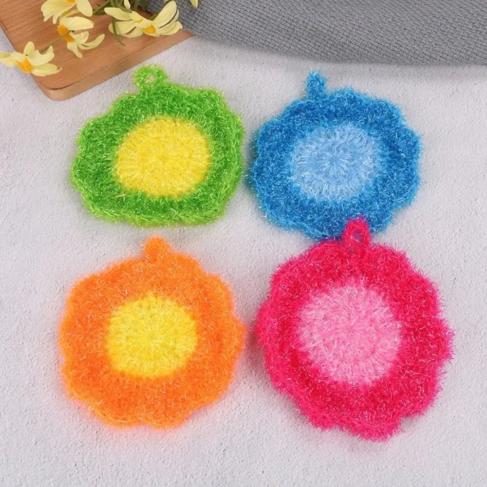 Four colorful acrylic non-stick dish sponges in green, blue, orange, and pink resting on a white surface.