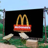 Grande bannière noire avec le logo McDonald's en arches dorées, éclairé de lumière chaude, en extérieur.
