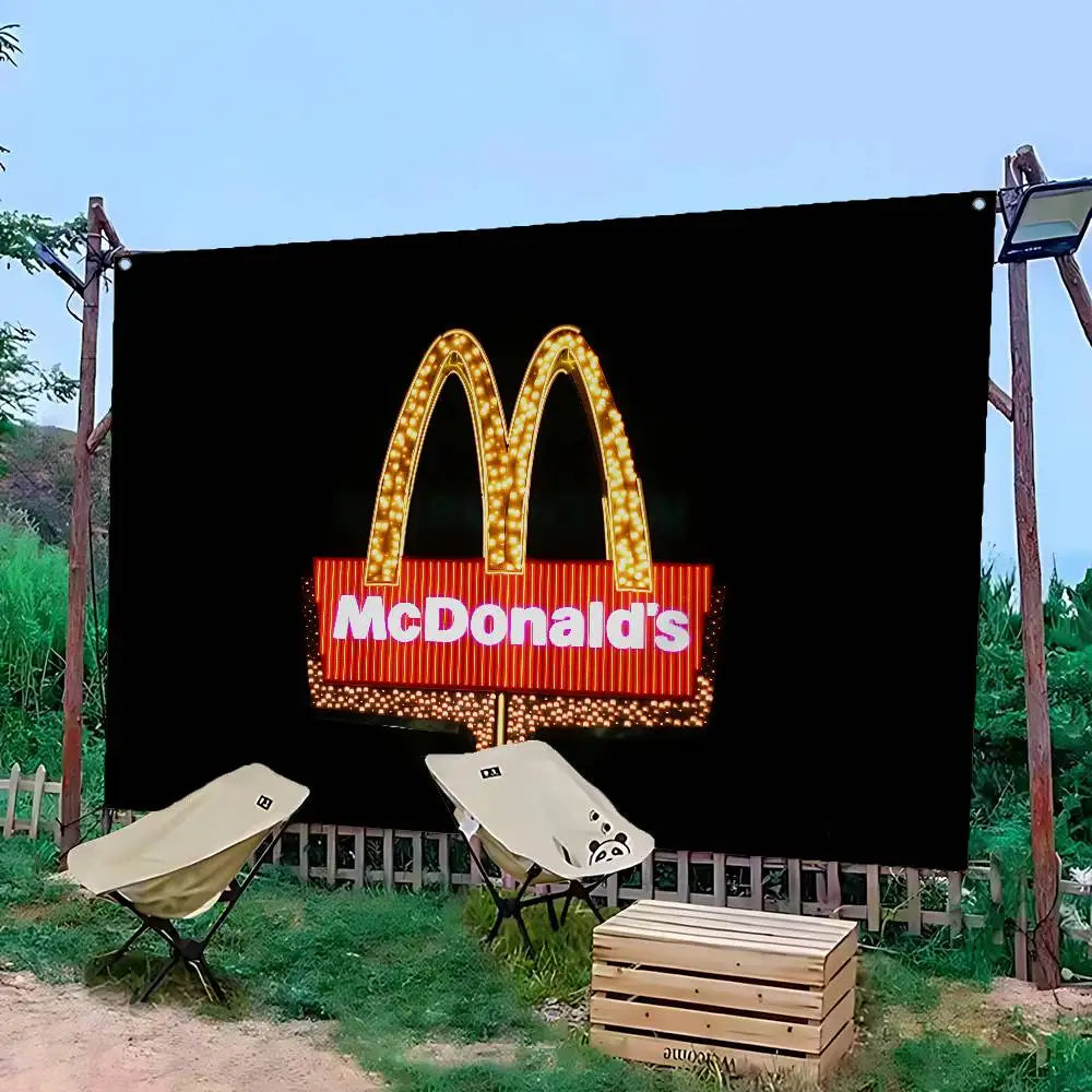 Grande bannière noire avec le logo McDonald's en arches dorées, éclairé de lumière chaude, en extérieur.