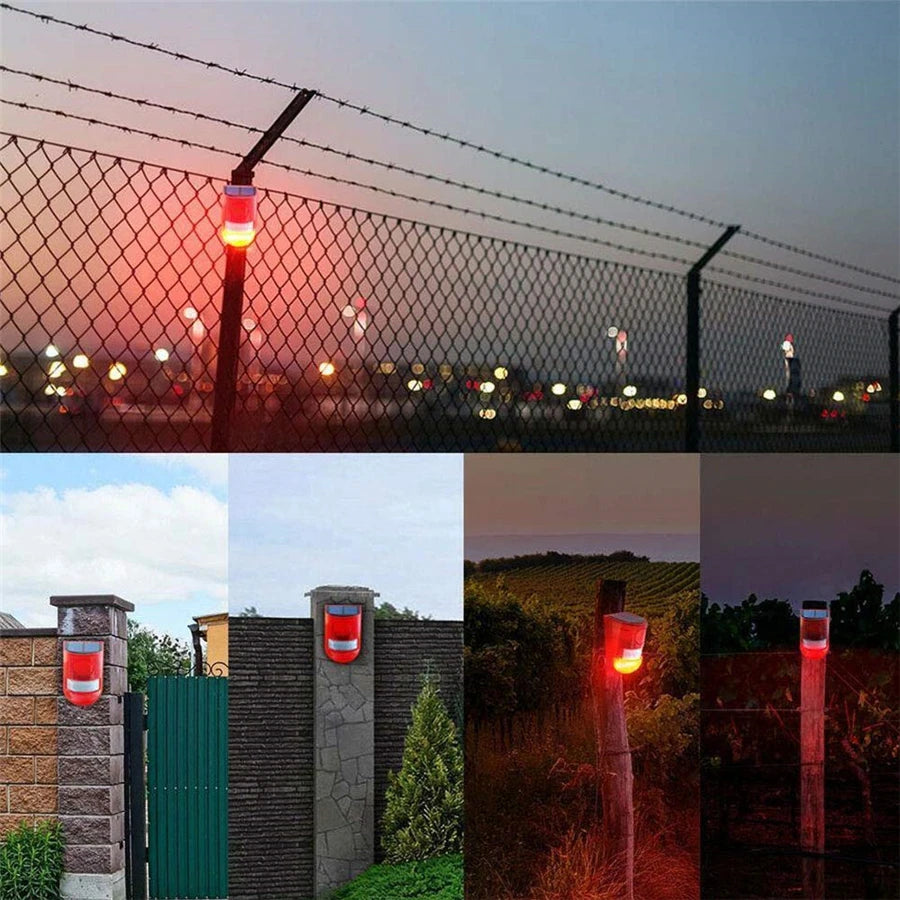 A solar-powered motion sensor alarm with a red strobe light mounted on a fence post at dusk.