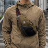 A person wearing a tan hooded jacket with an attached nylon crossbody bag.