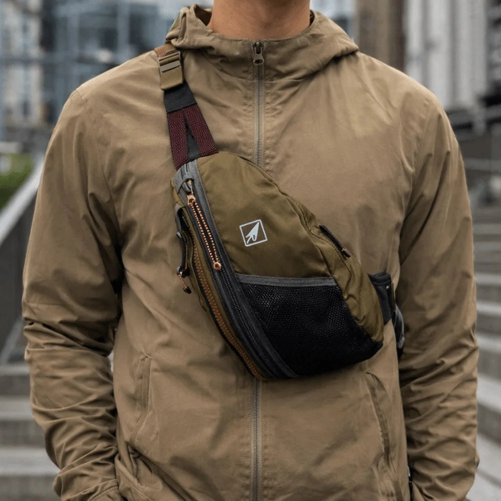 A person wearing a tan hooded jacket with an attached nylon crossbody bag.