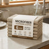 A stack of six beige microfiber cleaning cloths labeled as premium quality on a marble countertop.