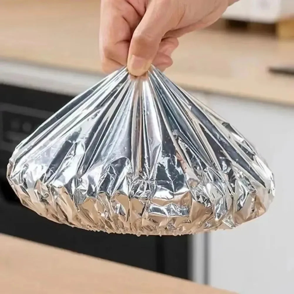 A hand is holding a reusable aluminum foil bowl cover, which is shaped like a cone.