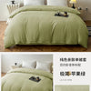 A light sage green washed cotton brushed duvet cover with white pillows and a dark tray on a wooden bed.