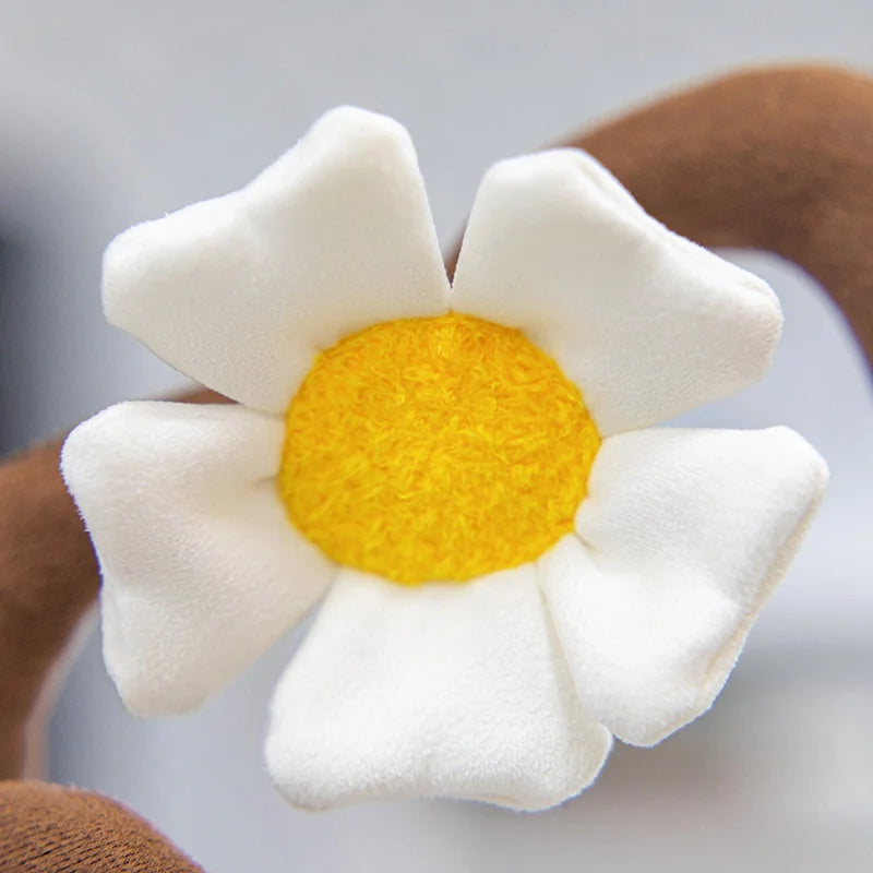 A white artificial flower plush doll with a yellow center is shown against a blurred background.