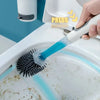 A hand is pressing a blue toilet brush into a toilet bowl, demonstrating the use of a refillable toilet brush set.