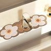 A modern silver faucet is placed on a wooden mat decorated with pressed floral patterns.