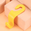 A pair of yellow universal car seat headrest hooks resting on a light pink rectangular surface.