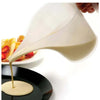 A plastic measuring cup with a long spout is pouring a light-colored liquid onto a black plate.