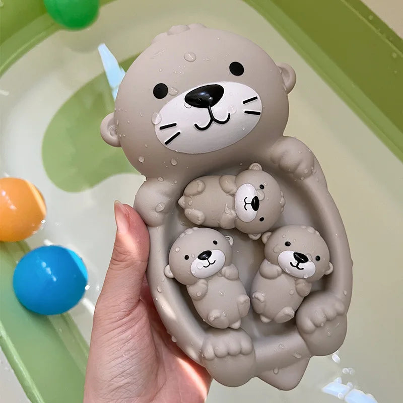 A hand holds a gray silicone bath toy set featuring a large bear and three small bear cubs, designed for floating play.
