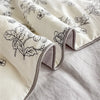 A close-up of a cream fabric with a black floral print, folded and draped on a light gray surface.