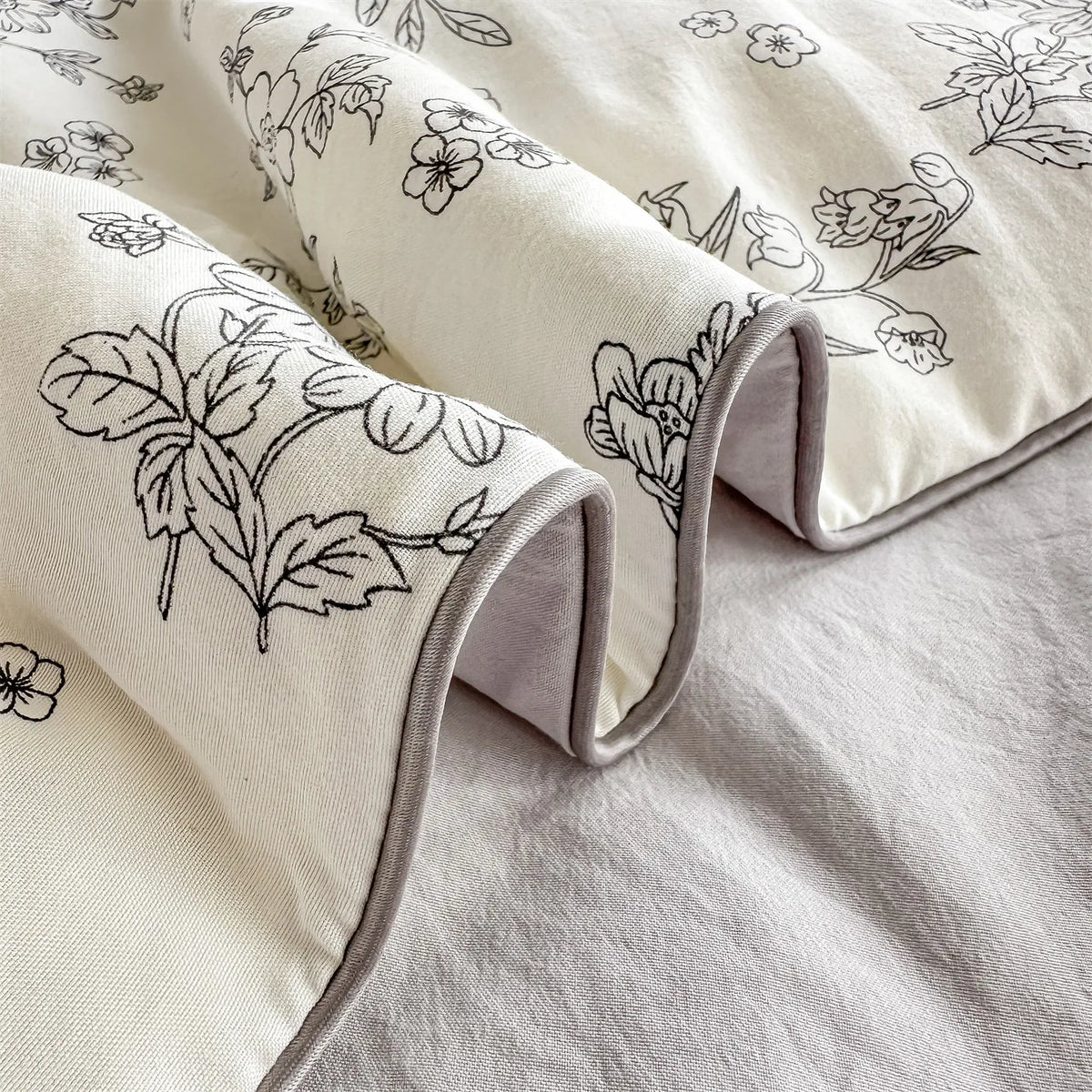 A close-up of a cream fabric with a black floral print, folded and draped on a light gray surface.
