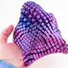 A hand holds a purple 3D printed articulated starfish fidget toy with a textured, scale-like surface.