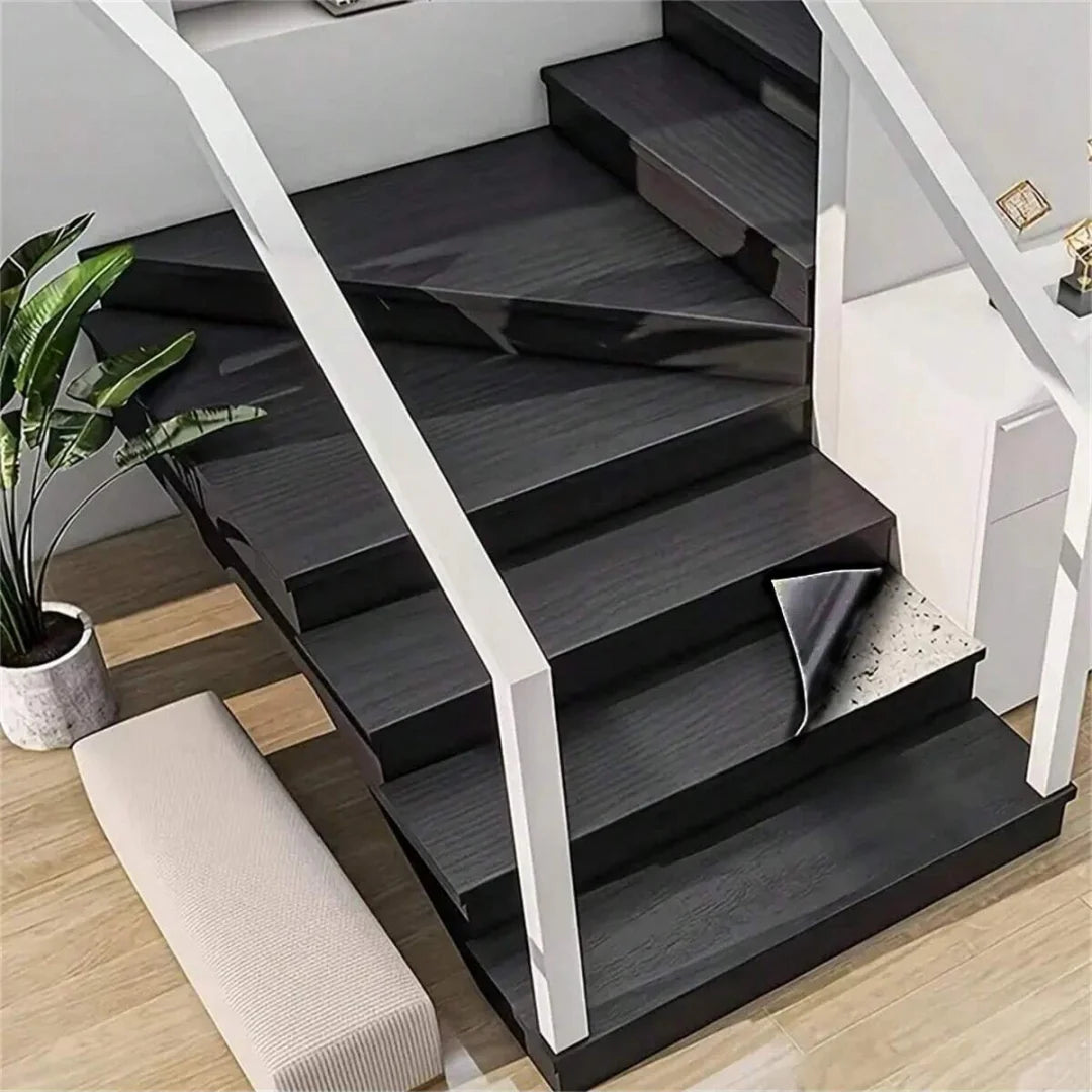 A modern staircase featuring dark wood grain treads and white railings, with a light-colored bench below.