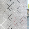A close-up of a wall covered in light gray, textured brick tiles with a repeating herringbone pattern.