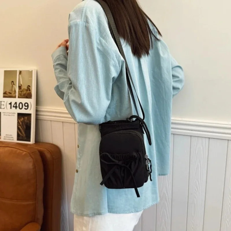 A light blue oversized shirt worn by a person, featuring a black Bow-Decorated Casual Crossbody Bag.