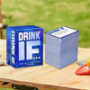 A stack of blue cards titled DRINK IF is placed on a wooden table outdoors.