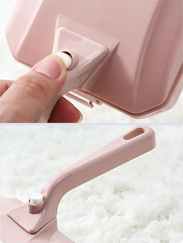 A close-up of a pink handheld double roller pet hair and debris brush being held by a hand.