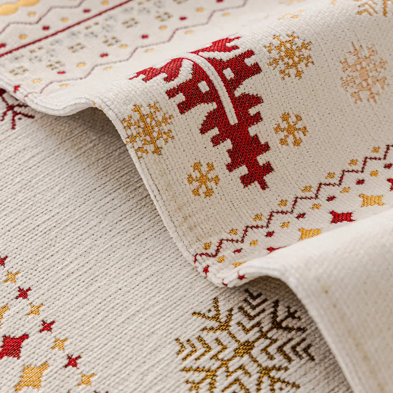 Close-up of a cream knitted fabric with red and gold snowflake patterns, showing a folded edge.