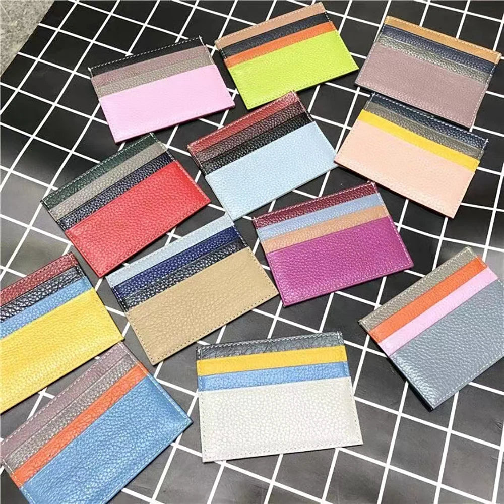 Colección de carteras de cuero genuino delgadas en colores pastel y tierra, dispuestas sobre fondo de rejilla negra.