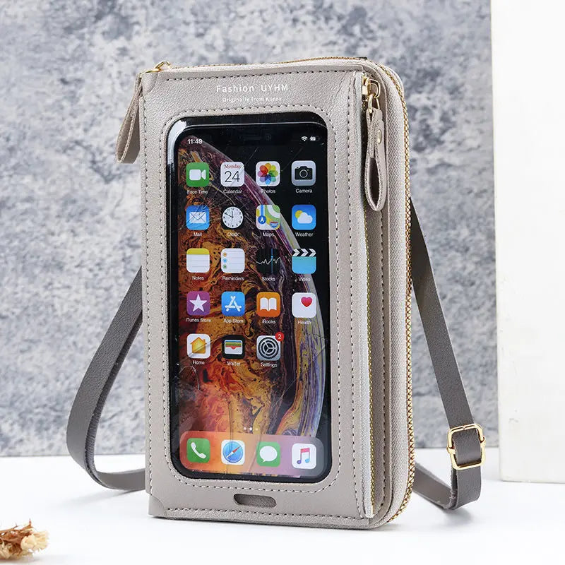 A light beige hands-free crossbody phone bag with a clear window showing a smartphone and card slots.