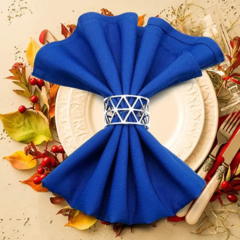 A bright blue fabric napkin tied into a decorative bow, placed on a white plate surrounded by autumn leaves.