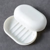 A white portable soap dish with a lid is shown open, displaying ribbed compartments for holding soap.