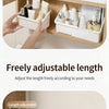 A hand is shown adjusting the length of a white cosmetic organizer with multiple compartments inside a wooden vanity cabinet.
