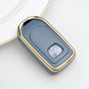 A close-up of a metallic gold TPU protective key case with a translucent blue lens covering a key.