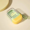 A leakproof travel soap case in light green and yellow plastic with a secure lid, resting on a beige surface.