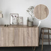 A wooden cabinet with a wood grain finish displays framed art and decorative items on a white wall.